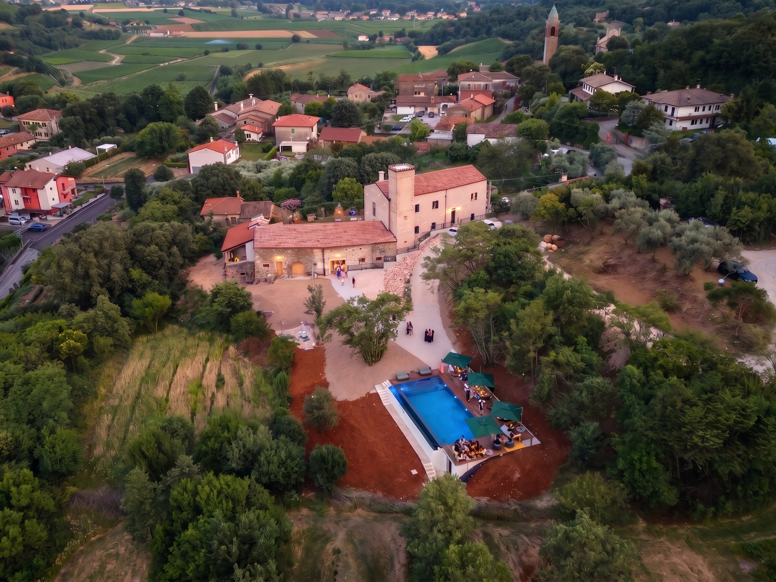 Tenuta Augusta pool and gardens at dusk with the Colli Berici and village beyond