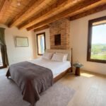 Suite Dogale bedroom with exposed brick, beamed ceiling and panoramic Colli Berici views