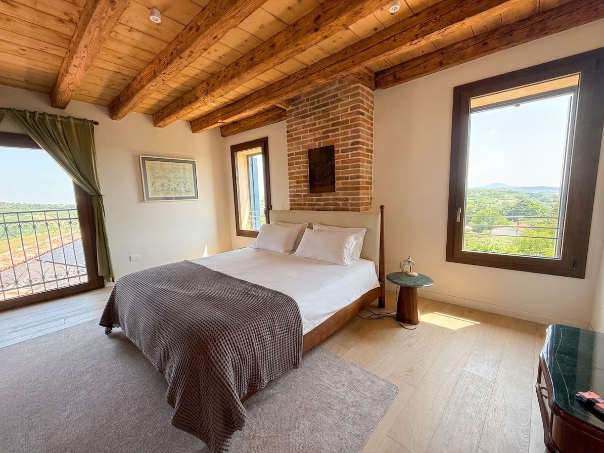 Suite Dogale bedroom with exposed brick, beamed ceiling and panoramic Colli Berici views